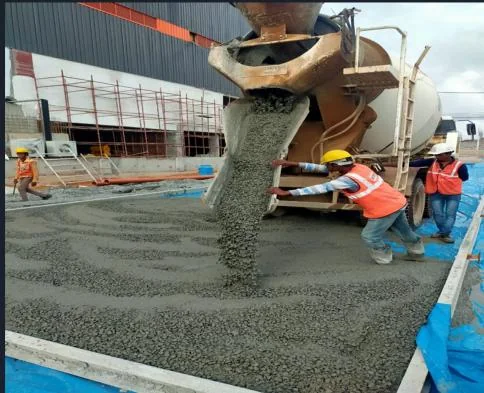 Concrete being poured from a transit mixer over a prepared bed